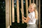Mädchen steht an einer Station mit Klangstäben aus Holz