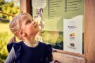 Mädchen in blauem Kleid steht vor einer Schautafel