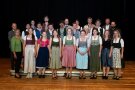 Personengruppe auf Holzboden vor schwarzem Vorhang